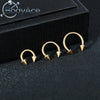 A set of gold-colored titanium steel nose rings with CZ crystals displayed on a black surface.