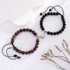 Two beaded bracelets made of natural brown and black stones with silver heart charms displayed on a white surface.