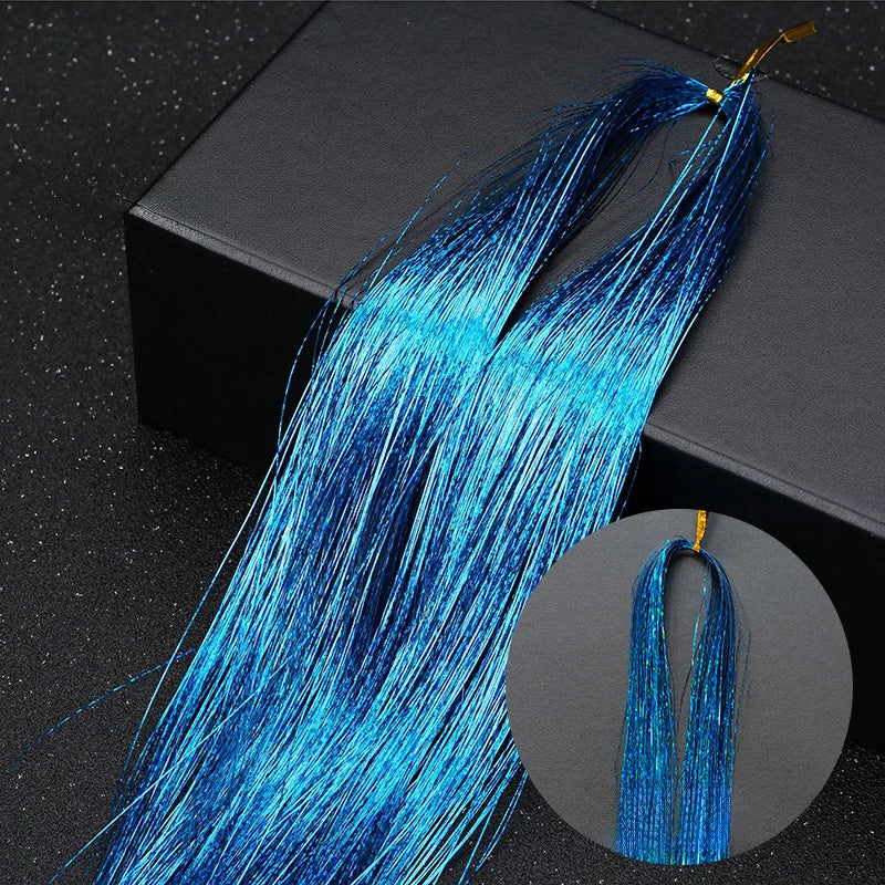 A bundle of bright blue glitter hair extensions with gold tips displayed on a dark surface.