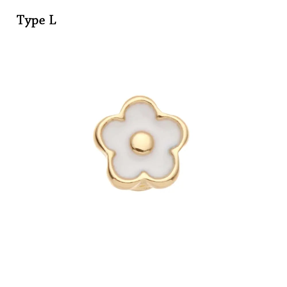 Adorno metálico dorado en forma de flor con centro blanco.