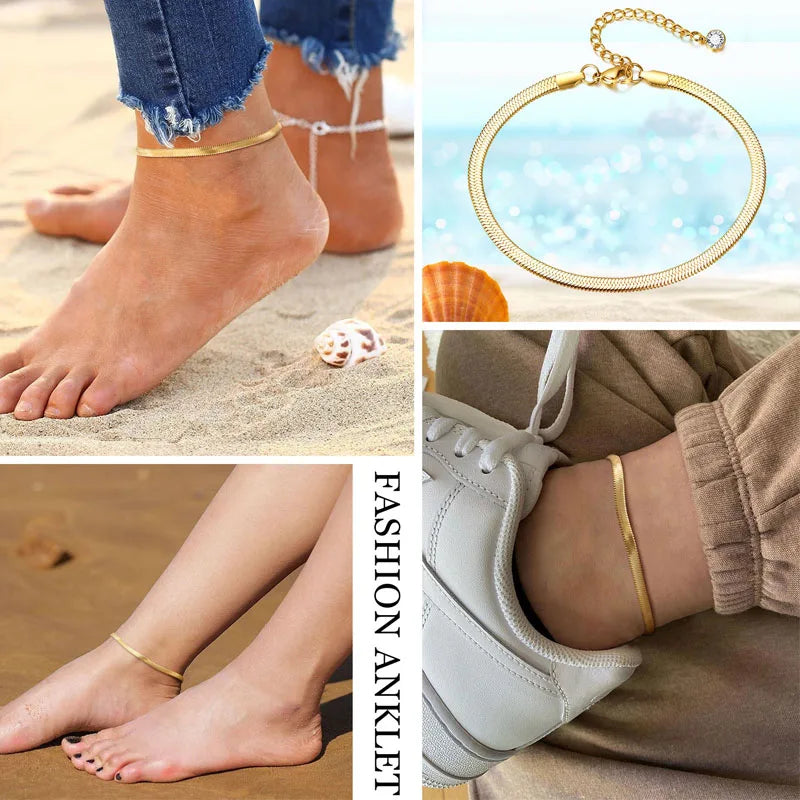 A gold stainless steel snake chain anklet worn on a foot against a sandy background.