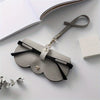 A light gray PU leather pouch and glasses case with a leather strap resting on a white surface.