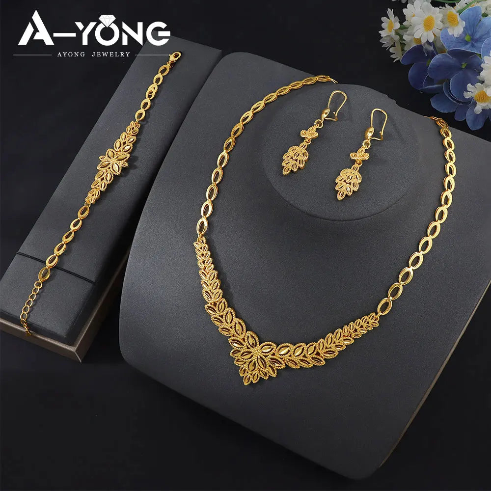 A set of luxury gold plated bridal jewelry including a necklace and matching earrings displayed on a dark surface.