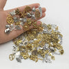 Eine Hand hält eine Sammlung gemischter tibetischer Silber- und Goldanhänger für DIY-Schmuck.