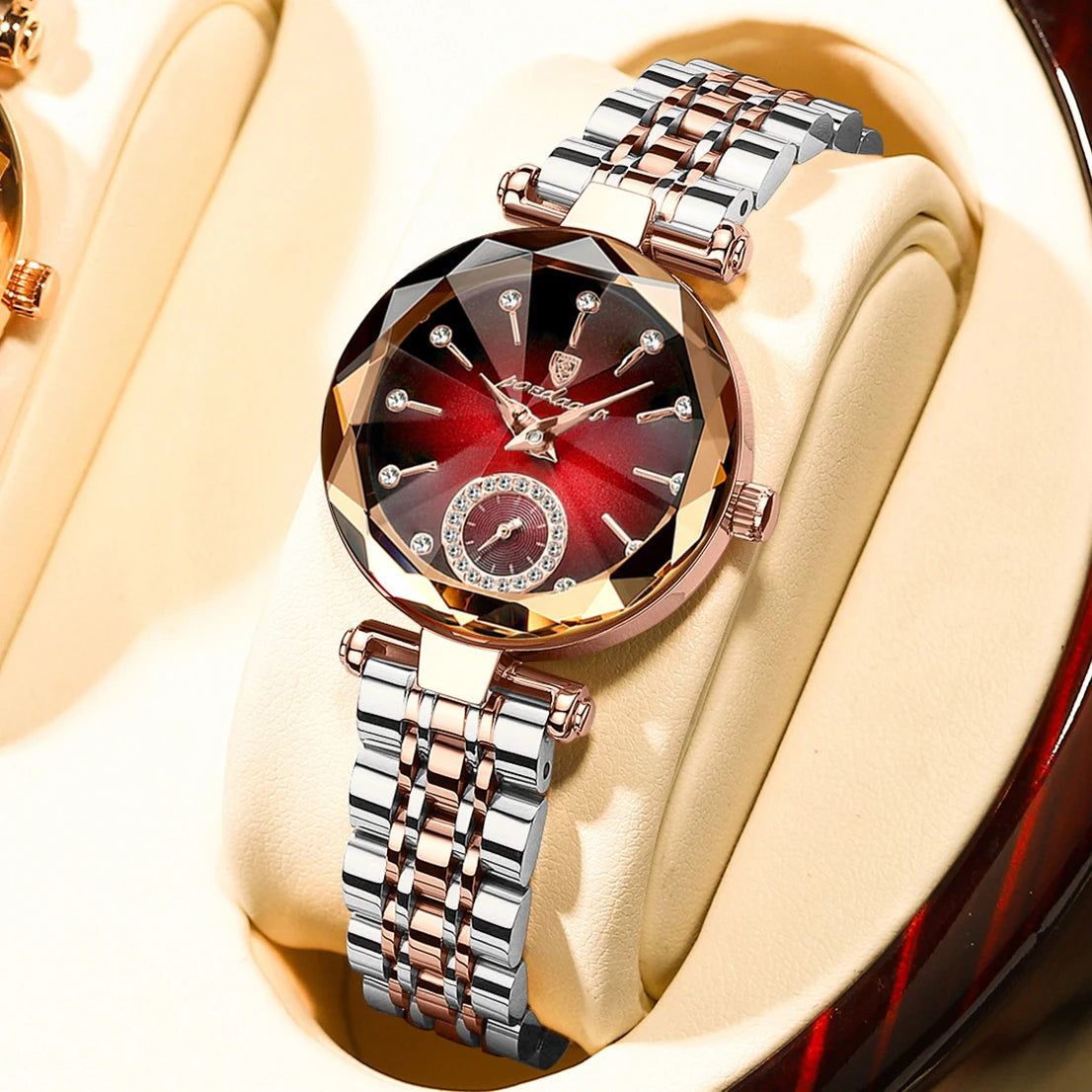 A close-up of an elegant stainless steel quartz ladies wristwatch with a red and gold dial and silver bracelet displayed on a