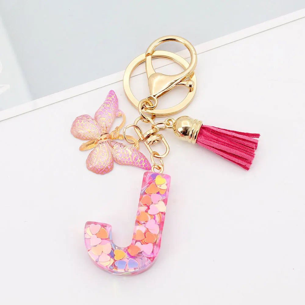 Alphabet letter acrylic keychain shaped like a letter J with pink butterfly and magenta tassel