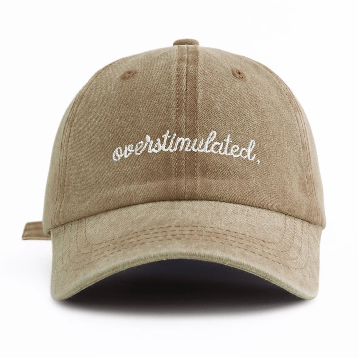 A beige washed baseball cap with white embroidered text that reads overstimulated