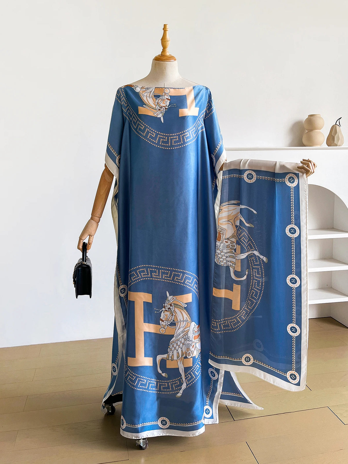 Una larga caftán abaya azul con estampado de caballo elegante y ribetes dorados, mostrada en maniquí.