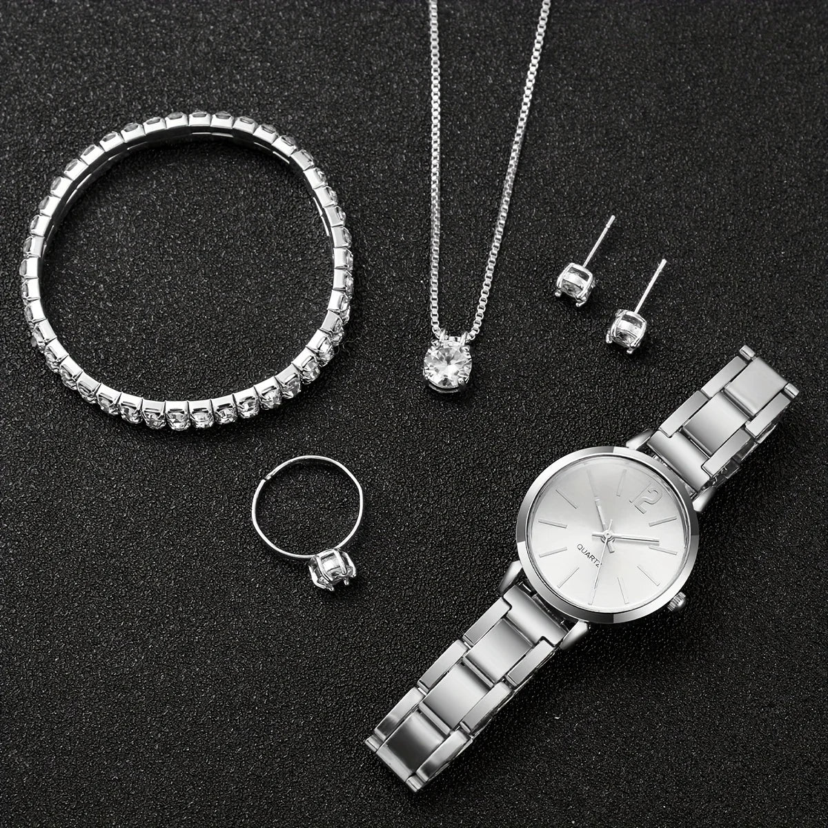 A set of silver diamond rings and a silver quartz wristwatch displayed on a black background.