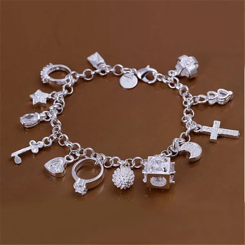 A silver geometric charm bracelet featuring various charms including stars crosses and hearts displayed on a brown surface.