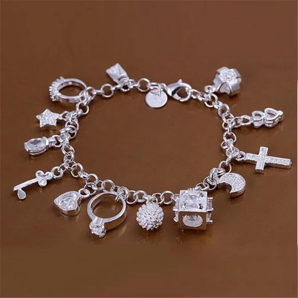 A silver geometric charm bracelet featuring various charms including stars crosses and hearts displayed on a brown surface.