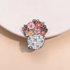 A set of enamel flower brooches featuring various colored flowers atop a silver globe design.