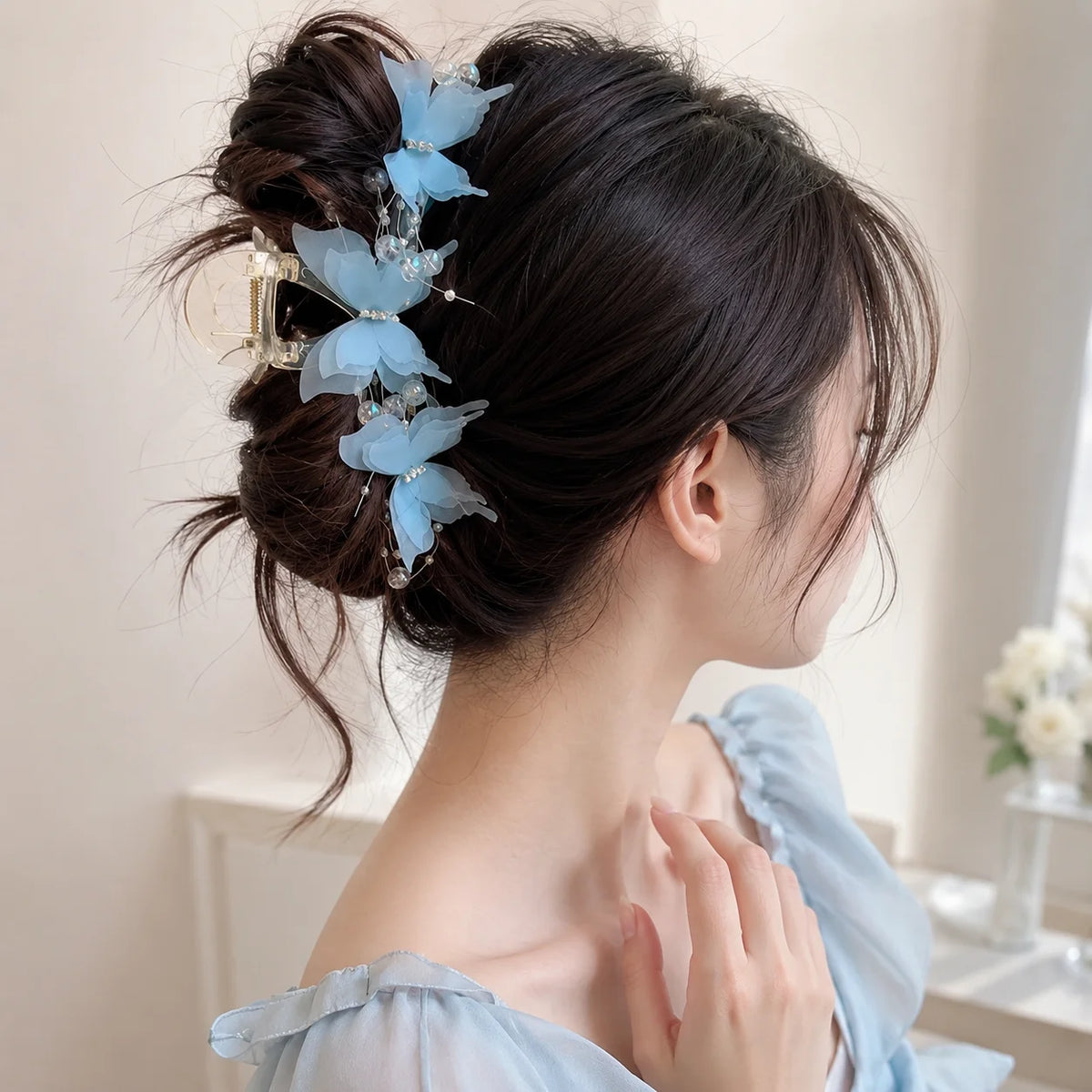 A woman's dark hair is styled in an updo adorned with delicate light blue pearl rhinestone butterfly hair claw clips.