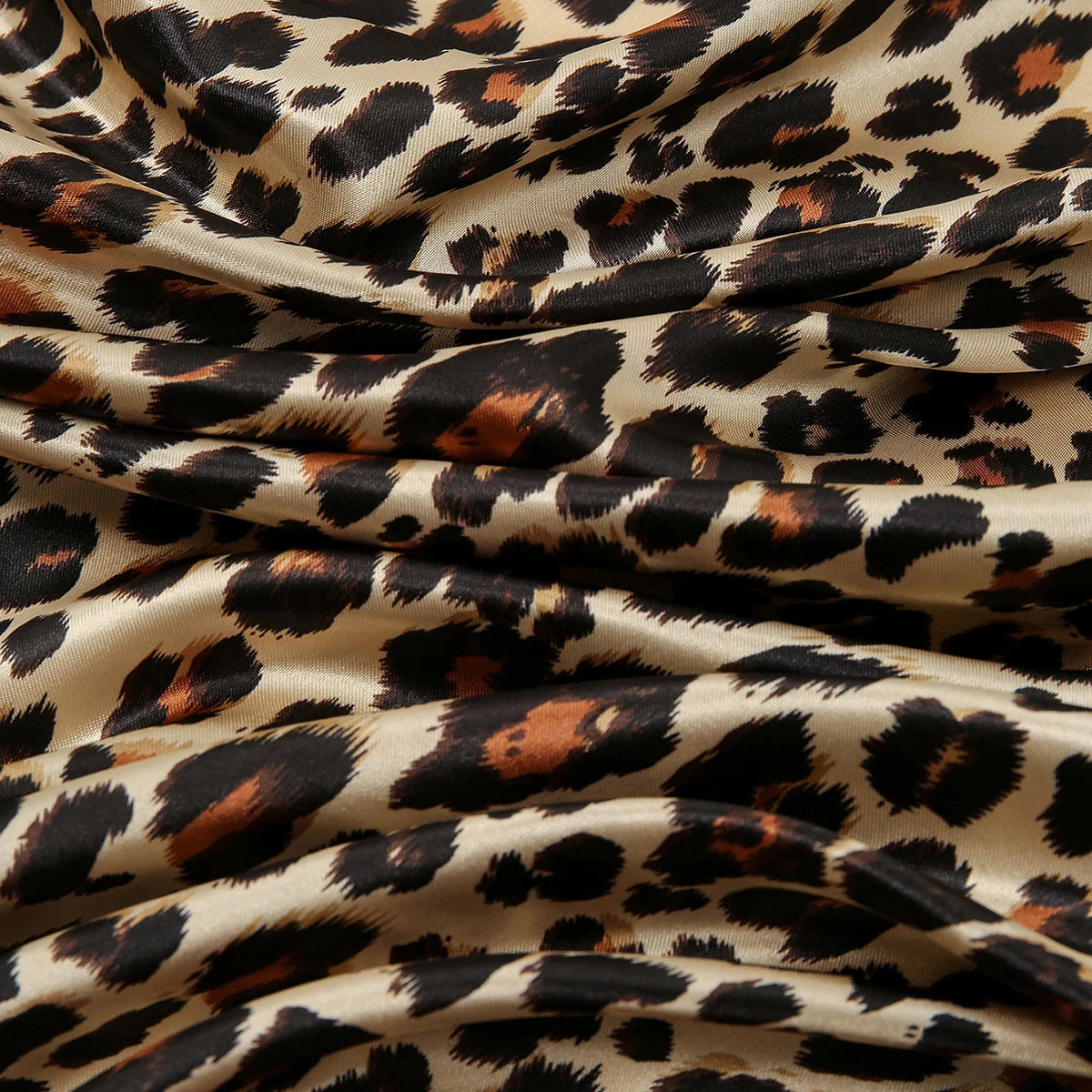 Fließender Stoff mit Leopardenmuster in Schwarz-, Braun- und Beige-Tönen.