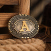 A vintage western belt buckle with an ornate gold and silver design resting on a wooden surface.