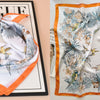 An orange and white silk scarf featuring a delicate floral print on a black background.