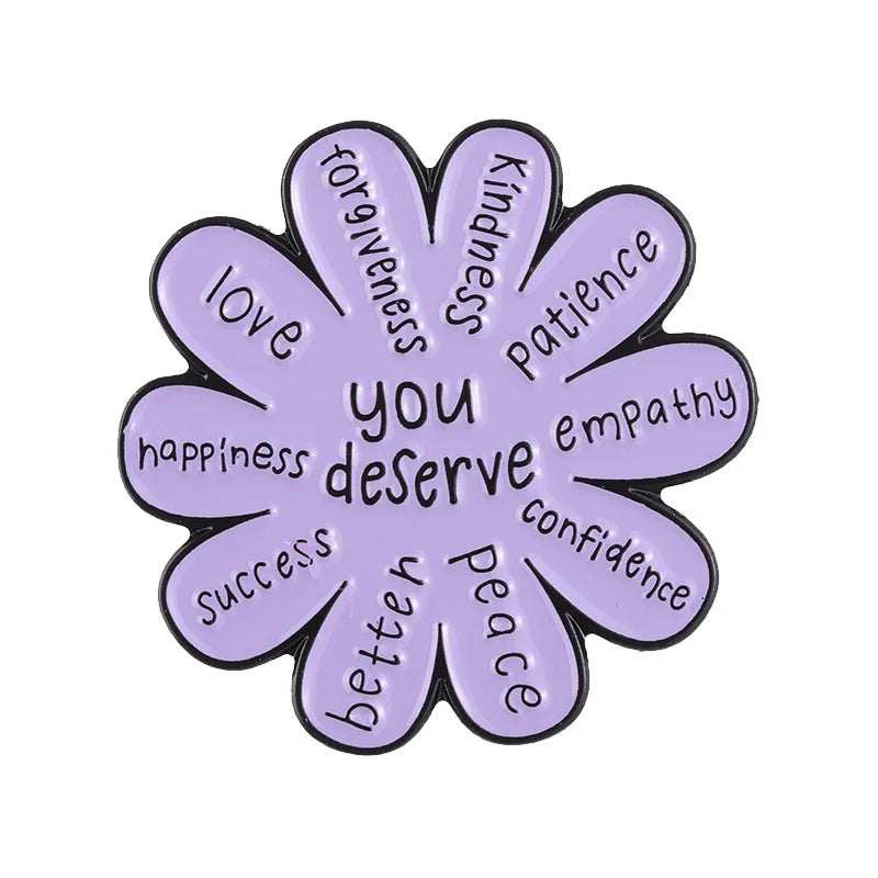 A purple enamel flower brooch set featuring words like love, kindness, patience, and success.