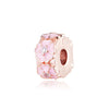 Un dije de oro rosa con diseño floral y una pequeña piedra transparente.