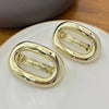 A pair of elegant gold metal oval hair clips resting on a white plate.