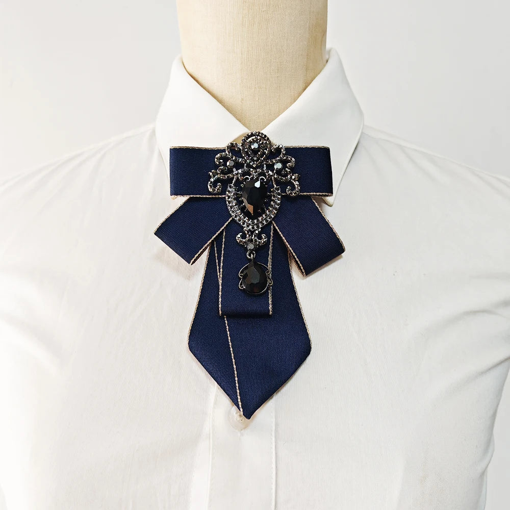 A navy blue handcrafted tie with diamond embellishments worn on a white collared shirt.