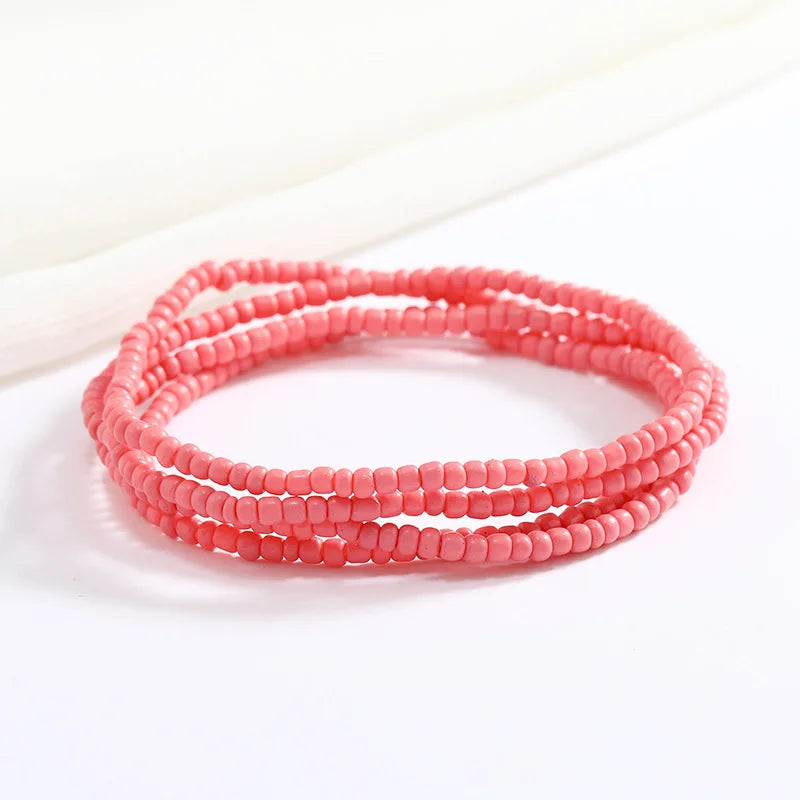 Una pila de pulseras de cuentas rosas sobre un fondo blanco.