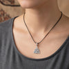 A close-up of a woman wearing a delicate sterling silver devil's eye charm necklace against a gray top.