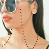 Close-up of a woman wearing gold crystal bead lanyards and chains around her neck and face.