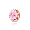 Un adorno de cuenta floral rosa con acabado dorado y una pequeña piedra transparente.