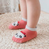 Rosa Baumwollsocken mit Panda-Gesichtmuster auf einem gewebten Matten.