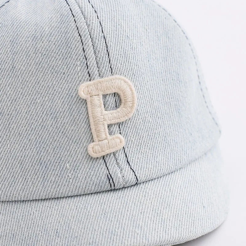 A light gray denim baseball cap featuring a stitched letter P on the front.