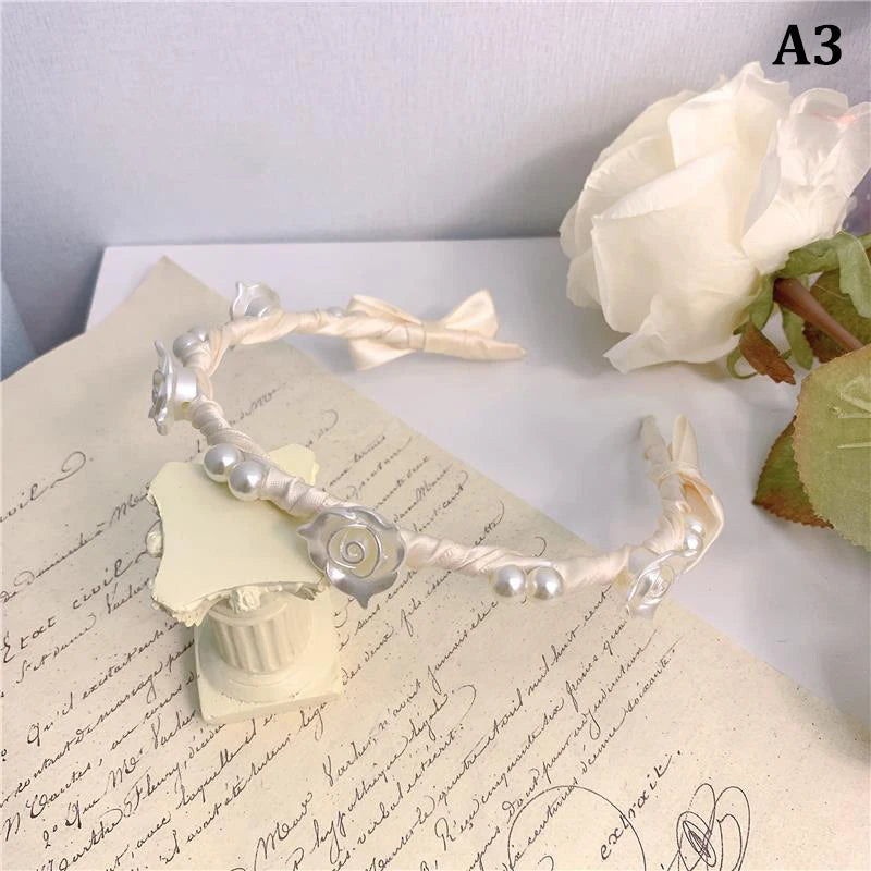 A delicate white rose vine headband hair accessory displayed on parchment paper next to a fresh white rose.