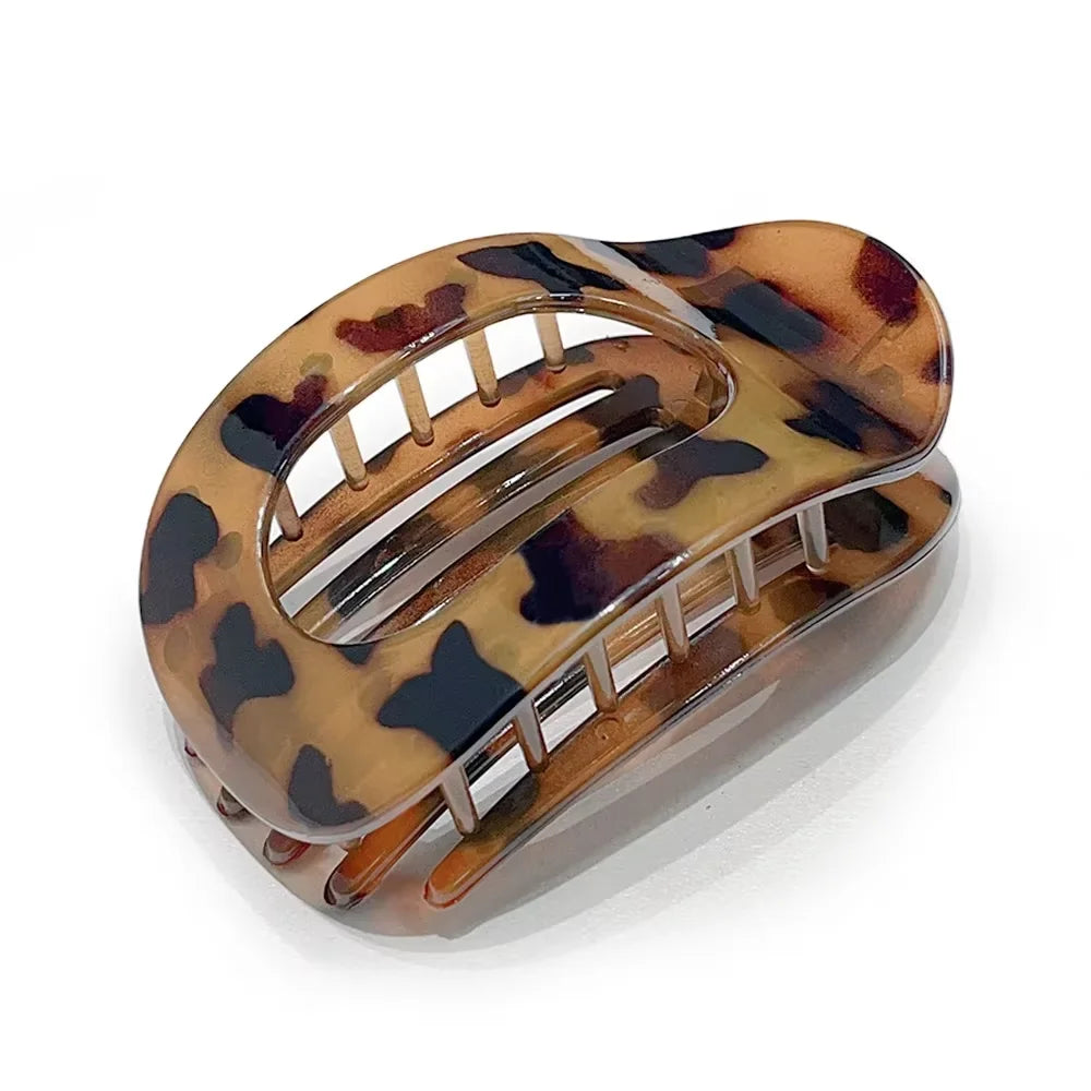 A matte oval hair claw clip with a leopard print pattern in shades of brown and black.