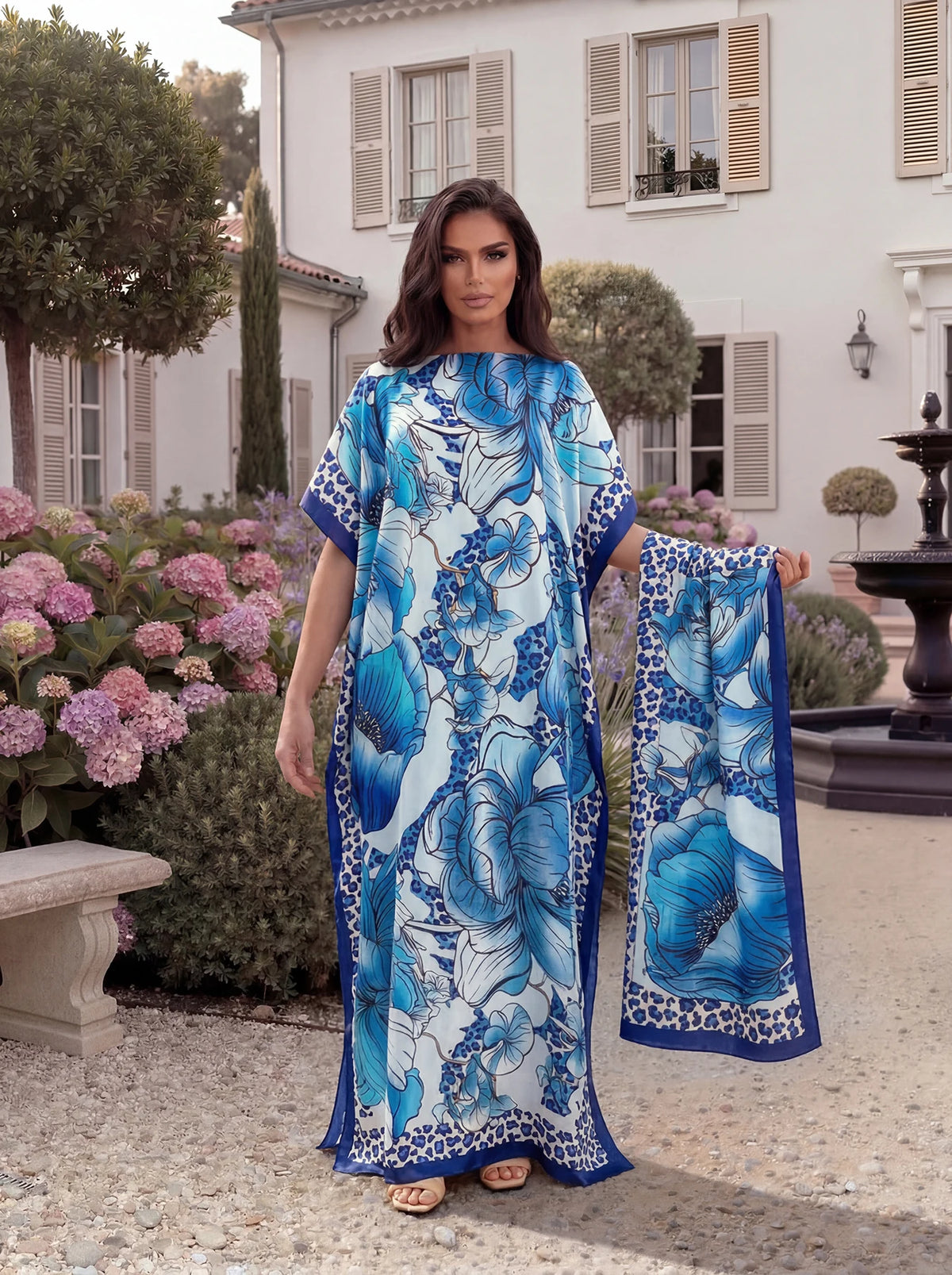 A woman models a blue and white tropical floral print abaya scarf outdoors.