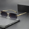 Gold-rimmed rimless square sunglasses resting on a dark gray slate surface.