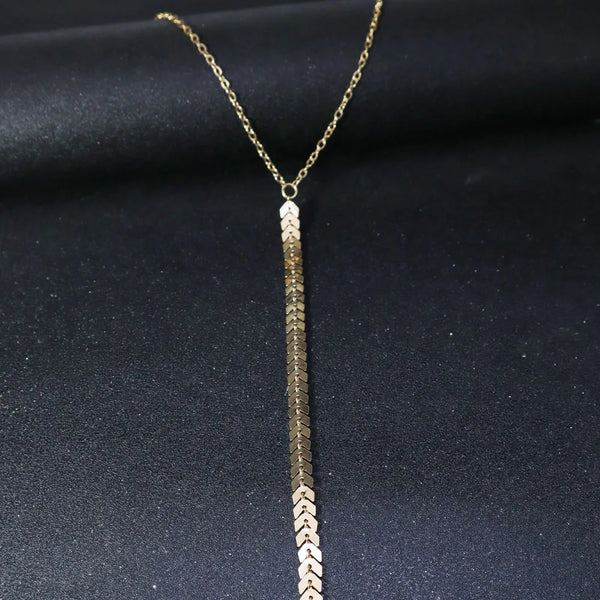 A gold minimalist wheat body chain necklace displayed against a dark background.