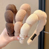 A hand holds a beige cloud sponge hair accessory headband with a black tag.