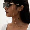 A woman wearing round metal beads sunglasses with a gold chain necklace.