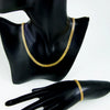 A close-up of an elegant gold plated necklace and matching bracelet displayed on a black mannequin.