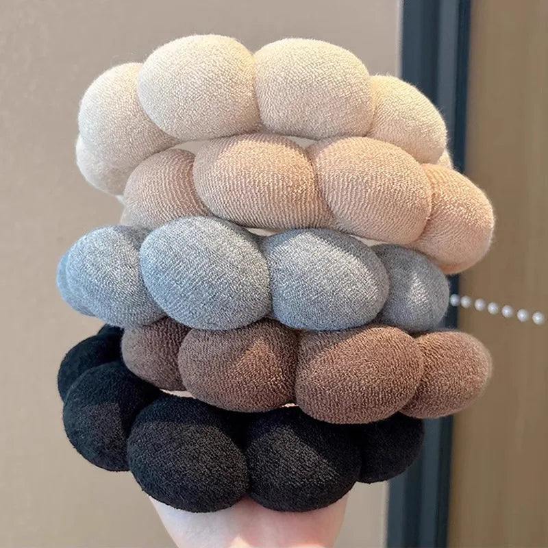 A stack of beige, gray, and brown cloud sponge hair accessories headbands
