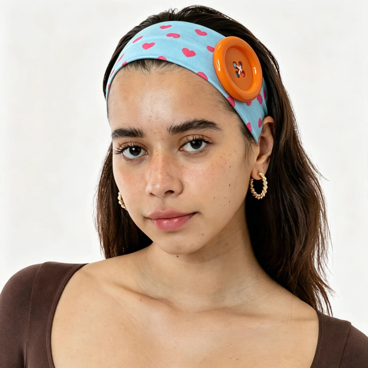 A young woman wearing an orange and blue polka dot button headband.