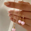 A hand models a dainty pearl jewelry set featuring matching earrings and a delicate necklace.