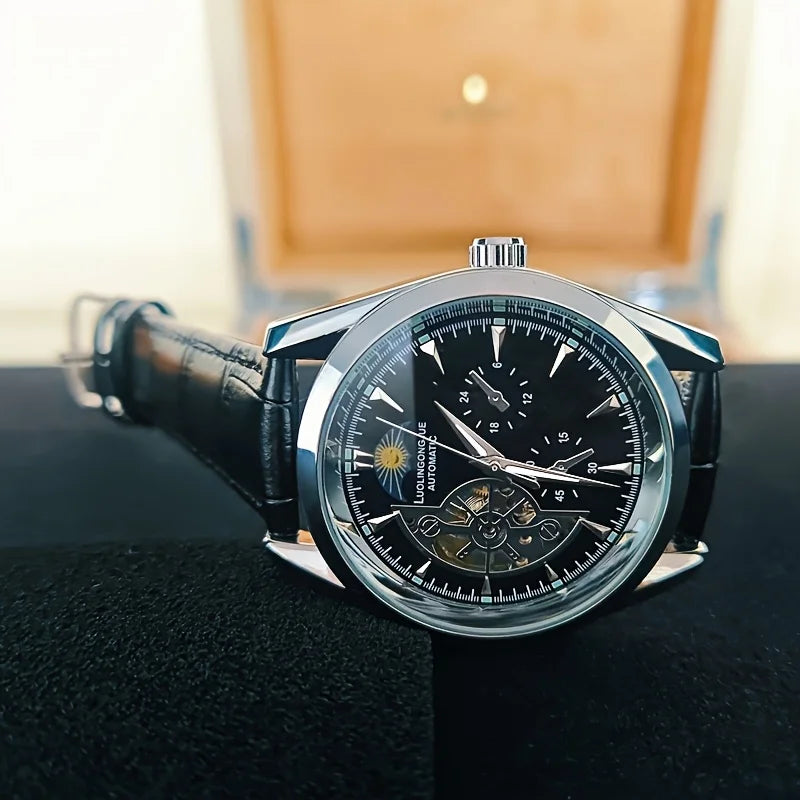 A close-up shot of a silver luxury automatic mechanical men's wristwatch resting on a dark surface.