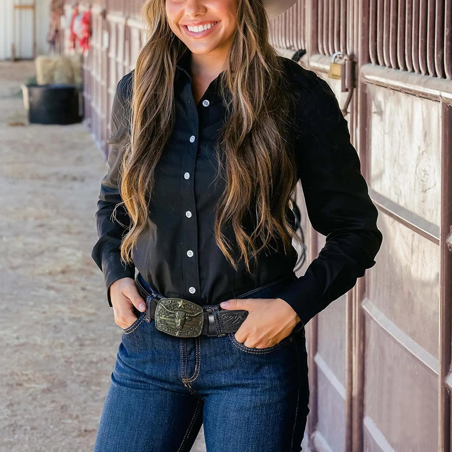 Una mujer vistiendo una camisa negra y jeans de mezclilla con un cinturón de mezclilla western grabado.