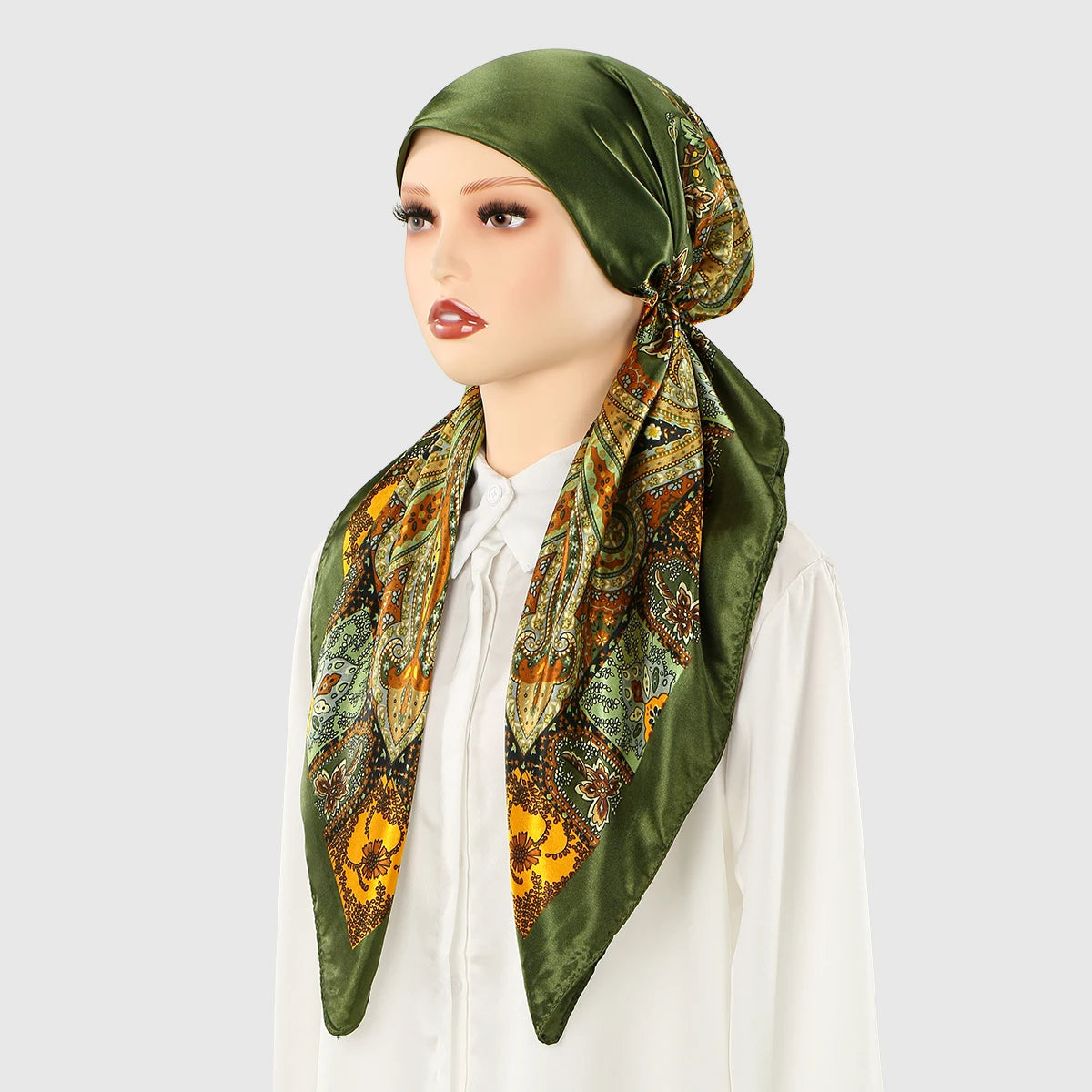 A woman models a satin silk hijab headband cap in olive green with an ornate floral print.