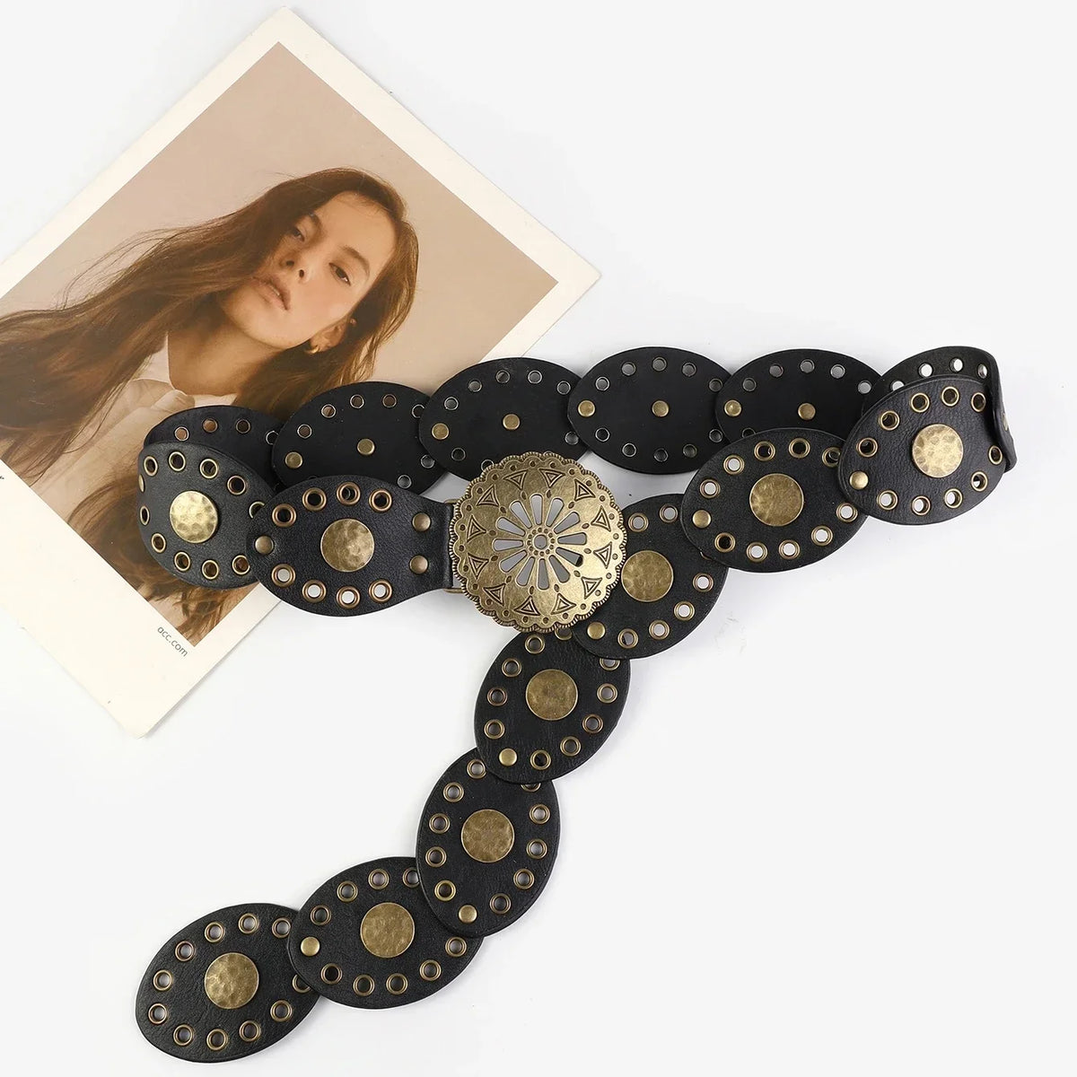 A black leather belt featuring round, hollow metal buckles and a decorative gold-toned centerpiece.