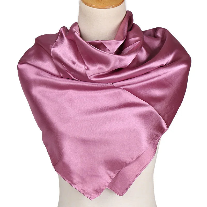 Una bufanda de seda satinada color malva brillante drapeada alrededor del cuello de un maniquí.