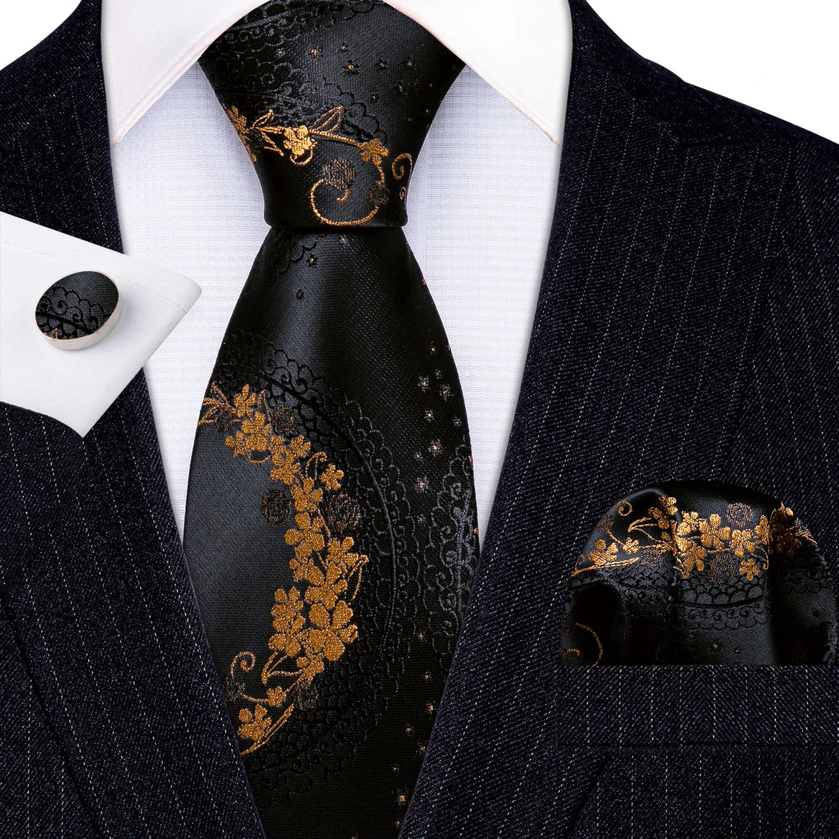 A black silk jacquard tie featuring gold floral embroidery worn with a dark blue suit jacket and white shirt.