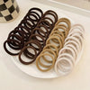 A collection of brown, beige, and white seamless elastic hair ties arranged on a white plate.