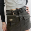 A close-up of a dark olive green skirt and belt featuring a black leather punk style belt with bullet studs.