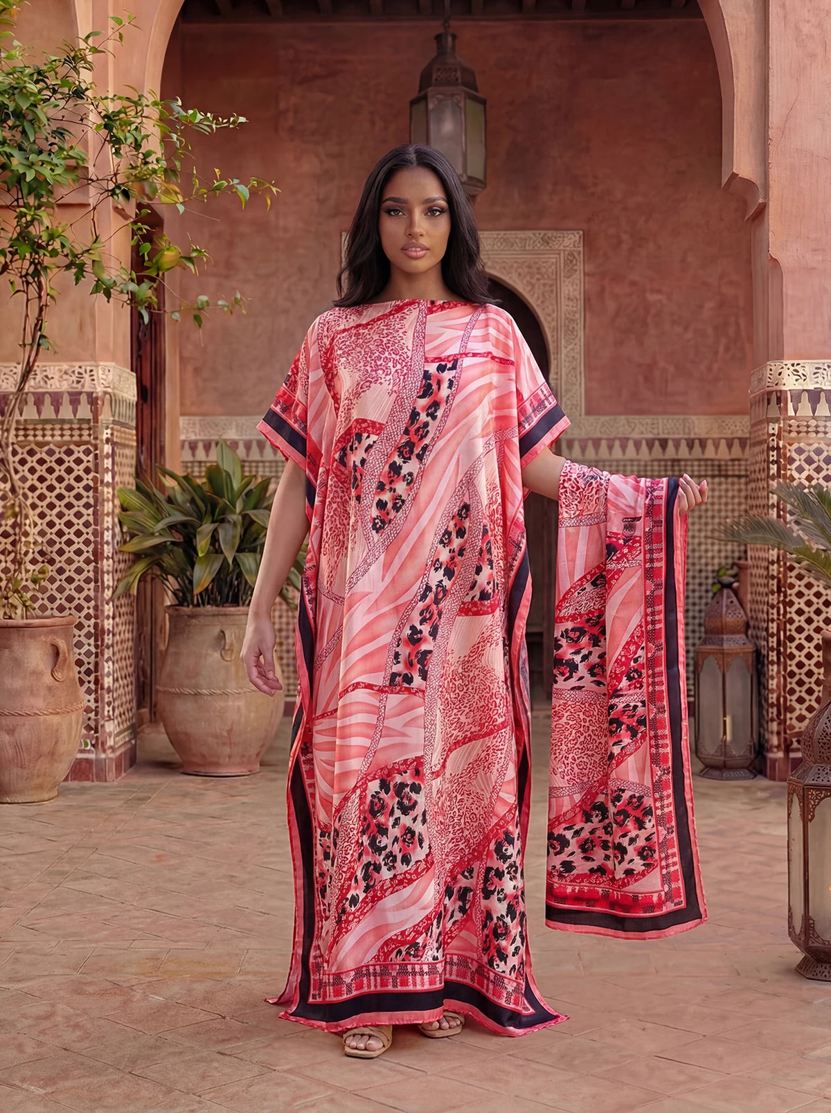 Femme portant une caftan abaya imprimé léopard et zèbre rose et noir dans une cour extérieure.